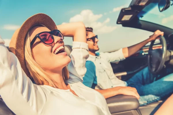 Coppia felice che guida una decappottabile sotto il sole.