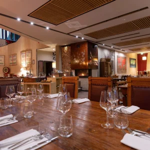 Interno elegante di un ristorante con tavoli apparecchiati e camino acceso.