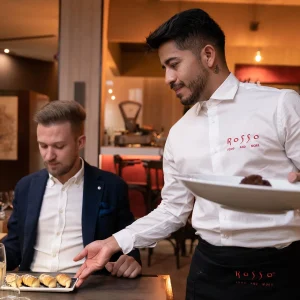 Cameriere serve dolci a un cliente in un ristorante elegante.